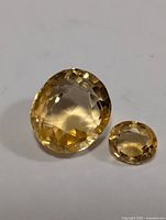 Two oval cut faceted citrine gemstones on a white background showing color and clarity.