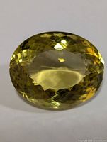Top view of oval faceted lemon green gold gemstone showing color and cut details.