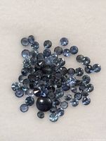 Multiple small blue sapphires including one larger cabochon sapphire on white background
