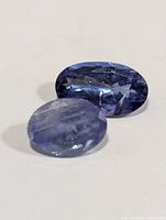 Two oval tanzanite gemstones on a white background showing color and cut details.