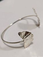 Close-up of one butterfly end of the silver bangle showing texture and shape.