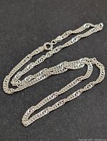 Silver chain necklace displayed on dark background showing full length and chain pattern