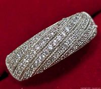 Close-up angled view of silver ring with multiple rows of small cubic zirconia stones set in a crisscross design.