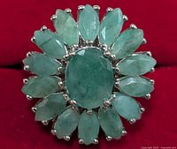 Top view showing the oval center emerald surrounded by marquise-shaped emeralds in a silver setting.