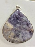 Front view of sterling silver pendant with large purple and beige marbled gemstone on white background