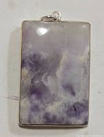 Front view of the rectangular silver pendant with a smooth bezel and natural purple-white marbled gemstone.