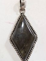Front view of diamond-shaped silver labradorite pendant showing the polished stone and decorative silver border.