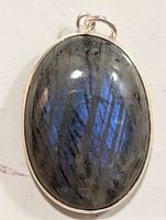 Close-up front view of oval labradorite pendant showing blue iridescent flashes and silver bezel setting with loop bail.