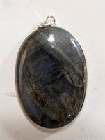 Front view of oval labradorite pendant in silver bezel setting showing polished stone surface and silver bail.