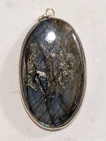 Close-up front view of oval labradorite pendant showing natural stone patterns and silver setting.