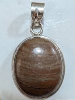 Top view of the silver pendant with oval polished brown gemstone showing natural striations