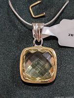 Close-up front view of the square cushion-cut lemon topaz pendant with silver bail and snake chain.