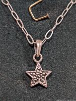 Close-up front view of the silver star-shaped marcasite pendant and part of the chain with larger oval links, showing the textured stones and bail attachment.