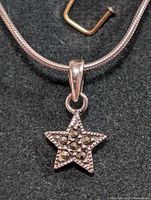 Close-up photo of the silver necklace chain with star-shaped marcasite pendant on black fabric background, showing front of the pendant.