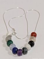 Front view of the necklace showing multi-colored gemstone beads on a silver chain with spring ring clasp.