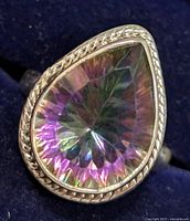 Close-up front view of silver ring with pear-shaped mystic topaz gemstone showing faceted, multicolored iridescent stone and decorative bezel detail.