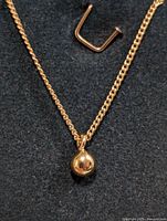 Silver chain necklace with spherical pendant and U-shaped metal clasp on black background.