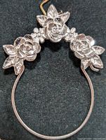 Front view of silver pendant showing raised three-rose flower design with leaf details on round frame