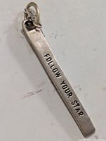 Top detail angle of silver pendant showing 'FOLLOW YOUR STAR' inscription and star-shaped charm on the loop.