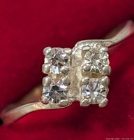 Close-up of silver ring size 4.5 with four clear stones arranged in a square cluster on a silver band.