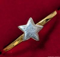 Close-up front view of silver star-shaped design on ring band showing brushed texture on star and smooth polished band.