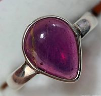 Close-up photo of the teardrop-shaped purple stone showing its color and internal inclusions in the silver bezel setting on the ring band.