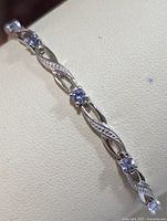 Close-up view of the silver bracelet showcasing detailed link design and prong-set round tanzanite stones.
