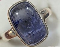 Close-up view of rectangular cabochon tanzanite gemstone in silver bezel setting on ring