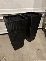 Two tall dark brown plastic flower pots with wicker pattern standing side by side against a white background.