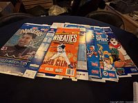 Photo of five unfolded cereal boxes laid flat on table showing sports-themed commemorative graphics