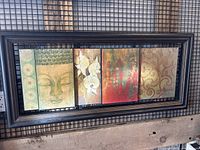Photo of Bombay Company modern framed art comprising four panels in one frame with different artistic designs including Buddha face, orchids, abstract and floral patterns.