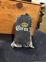 Close-up of black fabric Corona hammock pouch with white logo and crown.