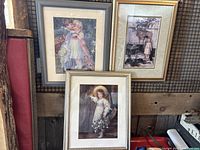Three framed vintage prints of children displayed against wooden wall