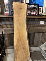 Photo of a single live edge wood slab bar top leaning against a wall with rustic decor in the background