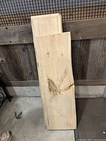 Three live edge wood shelves stacked leaning against a rustic wood backdrop. The top shelf has irregular natural edges and visible grain with some knots and color variation. Shelves thickness is about 1.5 inches.