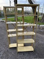 Photo of the beige metal shelving unit placed outdoors on a gravel surface, showing all six shelves and the frame structure.