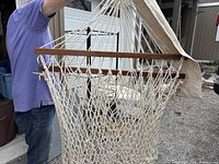 Hammock displayed showing detailed knotted rope structure and wooden spreader bars holding the hammock open.