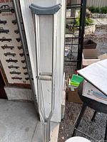 Aluminum crutches leaning against a wall with visible padded handles and arm support.