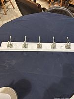Full view of the white wooden coat rack with five silver hooks on a dark blue tablecloth.