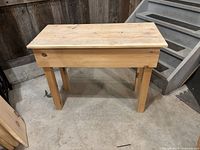 Photo of a natural wood finished end table showing rectangular top and four straight legs in a workshop setting.