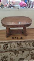 Front view of antique wooden double pedestal table with oval top, single drawer, and original wooden wheels placed in front.