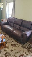 Full view of the sofa showing three seats, leather upholstery and nailhead trim