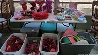 Overall assortment of Valentine and Easter themed seasonal decorations including plush toys, floral arrangements, garlands, tabletop decorations, and storage tubs beneath the table.