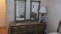 Front view of vintage dresser with detailed drawer fronts and two large mirrors on top.