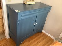 Front view of antique painted wood sideboard buffet showing the top surface, cabinet doors, white knobs, and decorative turned columns on front corners.