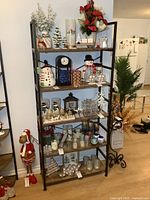 Front view of the assembled bookshelf with five wooden shelves held by a black metal frame. Shelves currently hold various holiday decorations (not included).