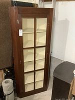 Front view of vintage wooden corner cabinet with single glass door.