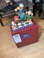 Disney Showcase Collection Navigating Nephews figure positioned on top of its original red box with MaxSold label.