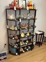 Front view of the metal frame shelf with various display items on it, showing six quarter-circle shelves forming a curved shape with solid black frame.