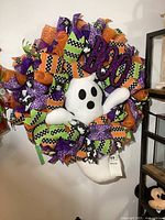 Full front view of the Halloween wreath showing the plush ghost center and surrounding curled ribbons with various Halloween patterns and colors.